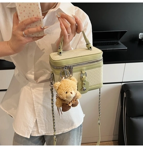 Détail d'un sac à main vert clair tissé avec un charmant pendentif en forme d'ours peluche