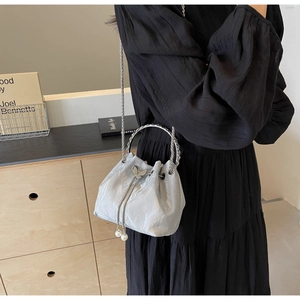 Détail du sac seau argenté avec boucle papillon et pendentifs en perles de nacre