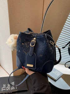 Deep blue bucket bag with snakeskin pattern, metal buckle and white plush charm accessory