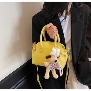 Detalle del bolso tipo concha amarillo en cuero lichi con colgante de perrito de peluche
