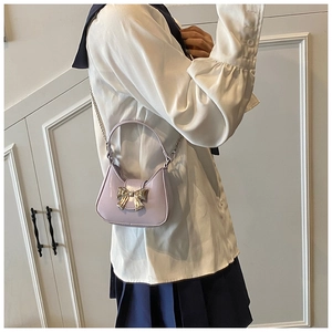 Détail d'un mini sac à main violet avec nœud argenté et chaîne porté par un mannequin