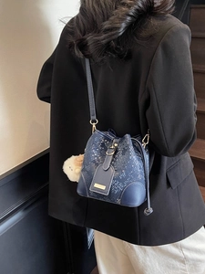 Navy blue snakeskin bucket bag with gold hardware and plush doll charm for women