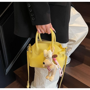 Bolso bandolera amarillo de piel granulada con un tierno colgante de perrito de peluche
