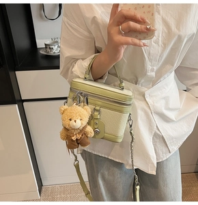 Détail du sac bowling tissé vert clair avec chaîne en métal et charm ours mignon