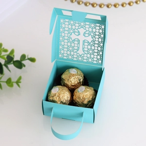 Detail showing laser-cut cross pattern and teal silk handle on wedding favor box