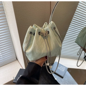 Détail du sac seau vert menthe avec fermoir papillon argenté et lanières en perles