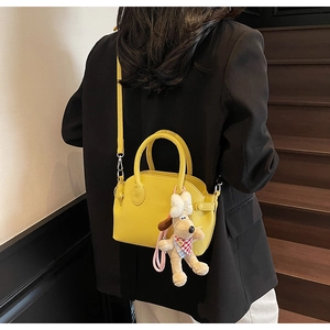 Detalle de bolso de mano amarillo con textura lichi y colgante de perro para mujer