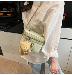 Vue détaillée du sac bandoulière vert menthe à motif crocodile avec breloque ours et chaîne