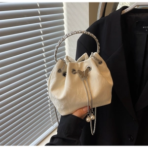 Détail du sac seau crème avec poignée en strass et fermoir à cordon en forme de papillon
