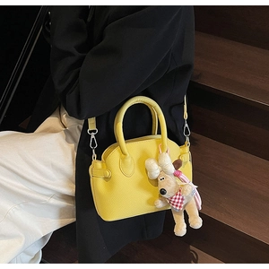 Close-up of yellow shell crossbody bag with litchi grain and plush puppy charm