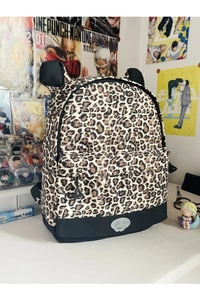 Detailed view of leopard print backpack featuring black bear ear accents and sturdy base