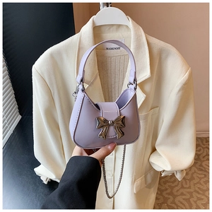 Mini sac à main lavande avec nœud métallique et bandoulière chaîne porté à la main