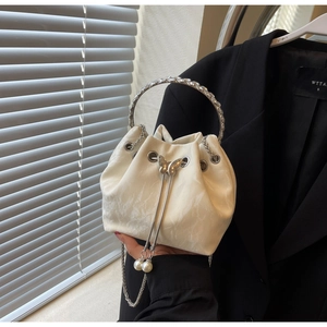 Détail du sac seau à cordon avec texture marbre, poignée en strass et pompons en perles
