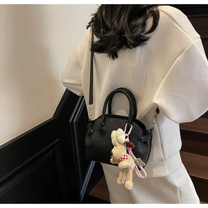 Detalle del bolso de cuero negro con colgante de cachorro de peluche sobre modelo