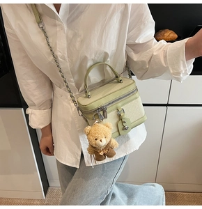 Détail du sac bowling vert clair tissé avec bandoulière chaîne et breloque ours
