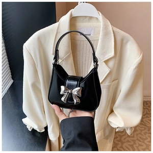 Vue détaillée du mini sac à main noir avec un nœud en métal argenté et finition lisse