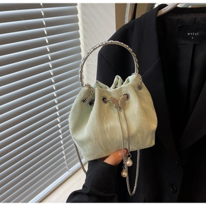 Détail du sac seau vert menthe avec poignée argentée, breloque papillon et perles