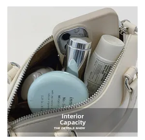 Internal capacity of off-white faux leather handbag showing phone and cosmetics