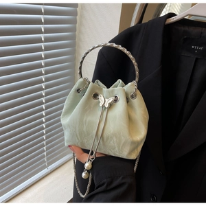 Détail du sac seau vert clair avec charms papillon argenté et pendentifs en perles