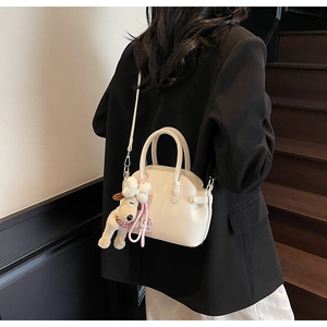 Detalle de bolso de piel granulada beige con un tierno colgante de perrito de peluche