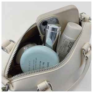 Detail view of the open off-white handbag interior showing storage for cosmetics