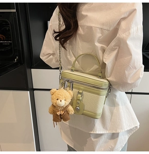 Détail du sac bowling vert pistache avec base tressée et breloque d'ours en peluche