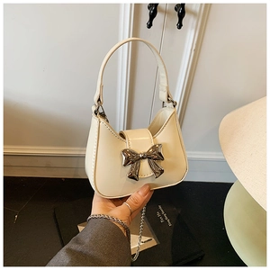 Détail du mini sac crème avec grand nœud en métal argenté et chaîne en métal élégante