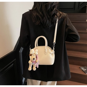 Bolso tipo concha crema con textura litchi y colgante de perro para mujer