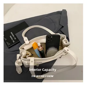 Detail of off-white leather handbag interior showing storage for phone and cosmetics