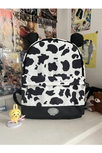 Detail of cow print backpack featuring animal ears and durable front zipper compartment