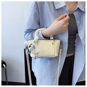 Detail showing creamy white mini saddle bag with lace, pearls and cartoon charm on model