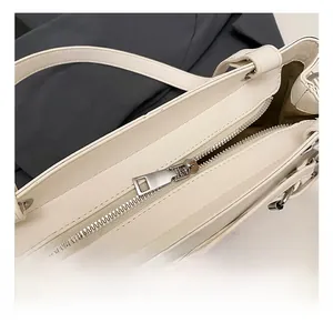 Close-up of high-quality silver metal zipper on minimalist cream white underarm bag
