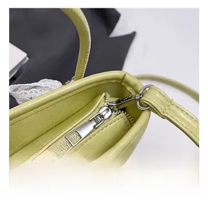 Gros plan sur la fermeture éclair en argent et la boucle de sangle du sac en cuir vert