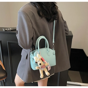 Detalle de bolso verde menta con textura lichi y un tierno colgante de perro de peluche