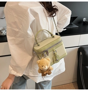Détail du sac bandoulière vert clair avec texture tressée et charm d'ours en peluche