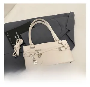 Detailed view of a white baguette shoulder bag with heart pendant on a grey suit jacket