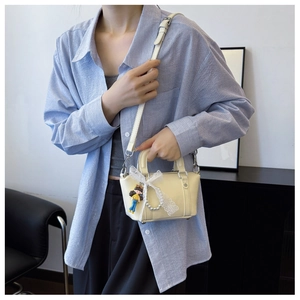 Close-up of off-white PU leather handbag with lace bow and cute doll charm detail