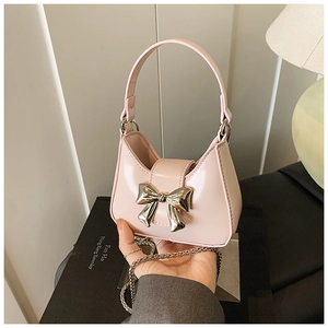 Détail du mini sac en cuir verni rose avec nœud métallique argenté et bandoulière