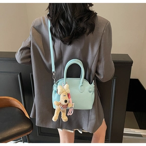 Close-up of light blue lychee pattern shell bag with a cute plush dog pendant charm