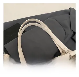 Detail of cream shoulder bag handle with precise stitching and silver metal hardware