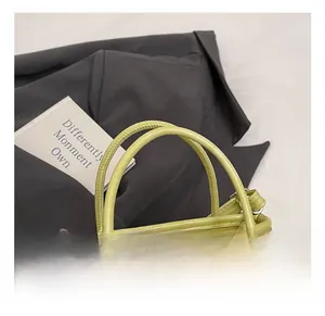 Détail du sac à main en cuir vert avocat montrant l'anse et les anneaux métalliques