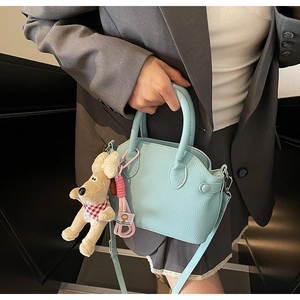 Bolso de cuero azul claro con colgante de perro de peluche usado por la modelo