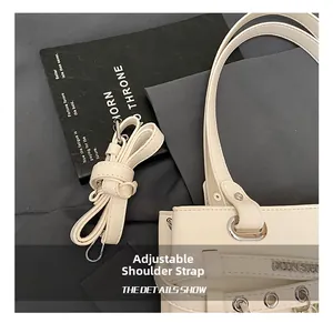 Detail of adjustable PU leather shoulder strap with silver metal buckle on cream handbag