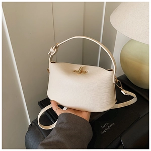 Detail der cremefarbenen Handtasche aus Leder mit goldener Schließe und verstellbarem Gurt
