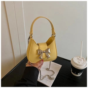 Détail du mini sac jaune avec nœud argenté métallique et bandoulière chaîne amovible