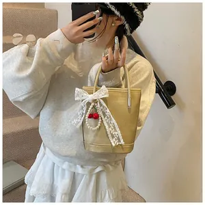 Sac seau doré clair chic avec nœud en dentelle et breloque cerise et perle raffinée
