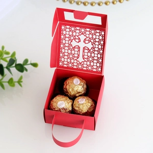 Detailed laser-cut red wedding favor box with cross design and red ribbon handle