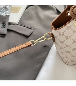 Gros plan des crochets dorés et finitions en cuir marron sur le sac seau monogramme