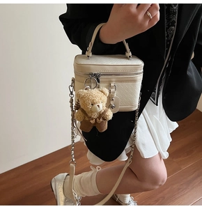 Détail du sac bowling tressé crème avec pendentif ours et bandoulière en chaîne