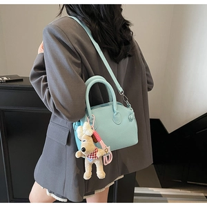 Detail of light blue lychee pattern shell bag with cute plush puppy charm accessory